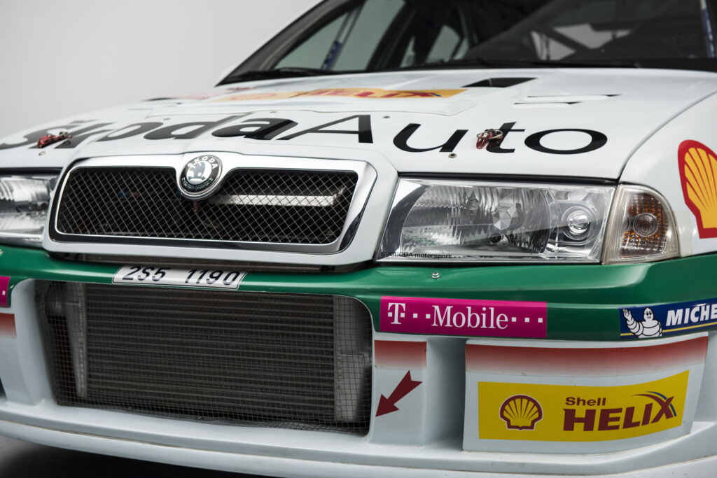 Front bumper and grille of a white Skoda Octavia WRC rally car featuring T-Mobile and Shell Helix sponsor decals.
