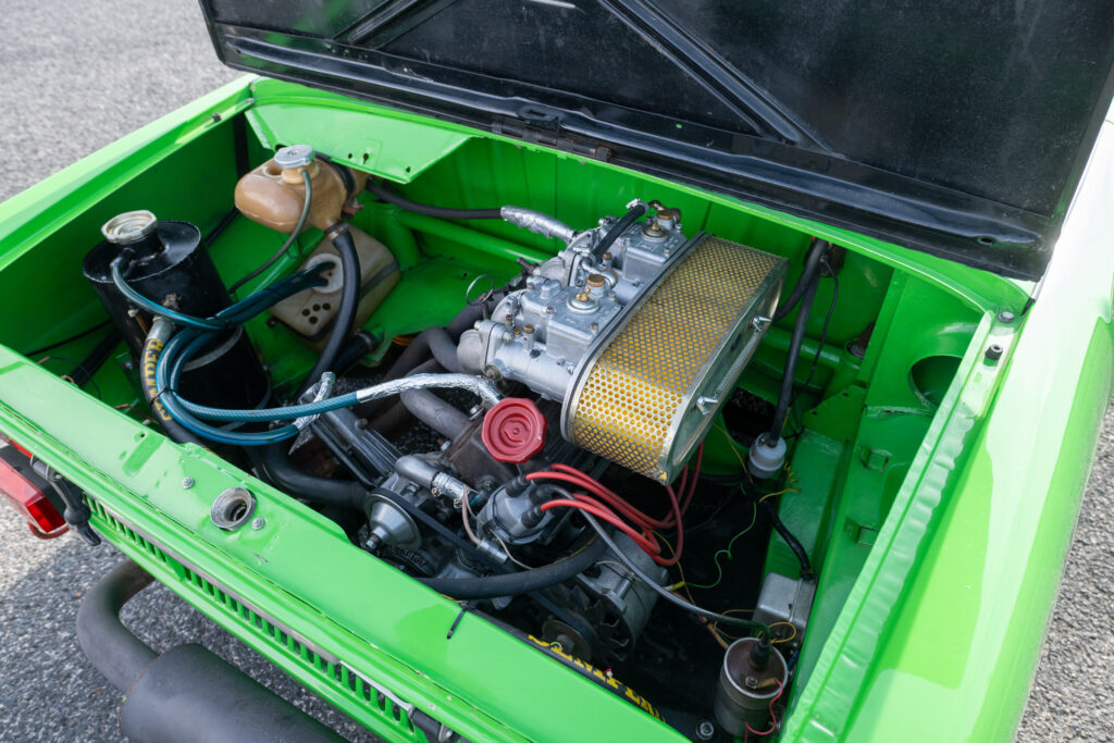 Vintage green car rear engine bay featuring a Weber carburetor and custom yellow air filter.