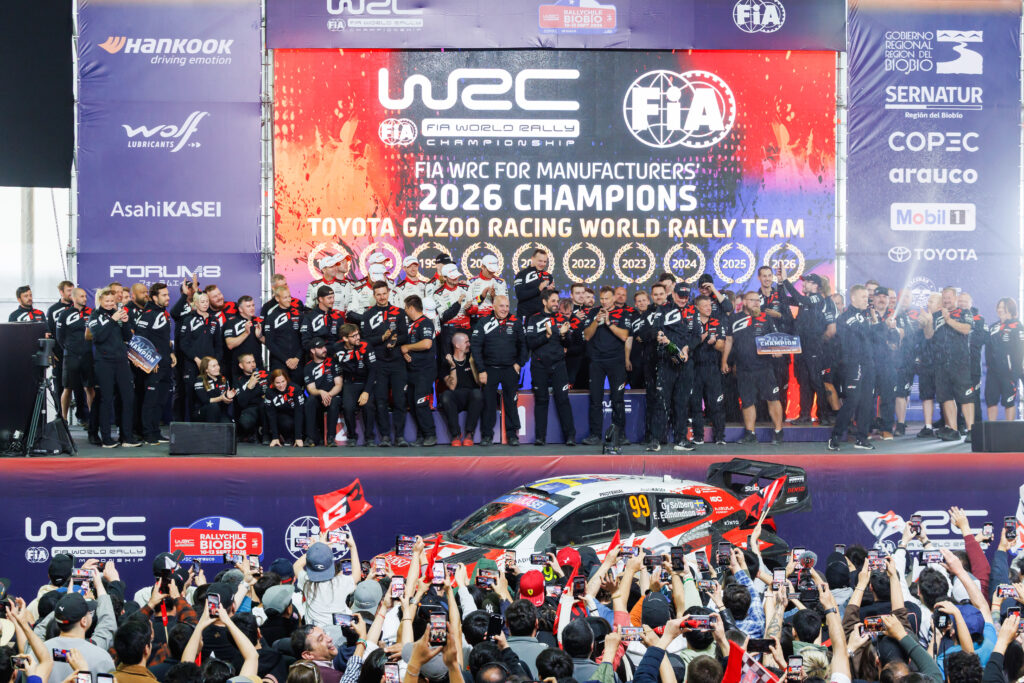 Toyota Gazoo Racing team celebrates winning the 2026 FIA WRC Manufacturers' Championship on stage with a rally car.