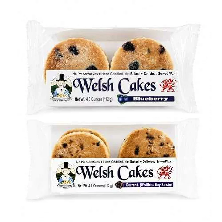 Traditional Welsh cakes in blueberry and currant flavors, packaged in clear plastic wrap on a white background.