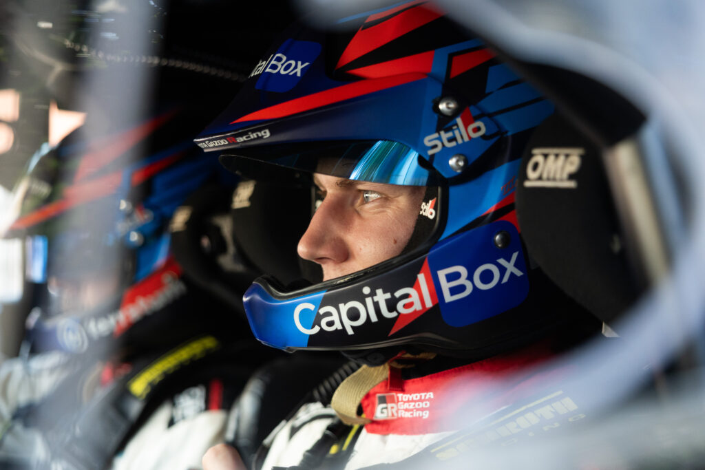Toyota Gazoo Racing rally driver wearing a blue Stilo helmet with CapitalBox branding inside a race car.